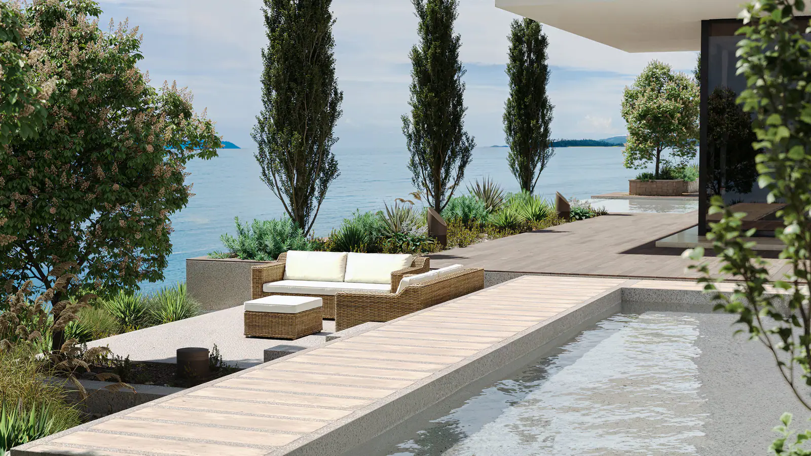 An oceanfront pool terrace with lounge seating, bronze bollard speakers set into the planting