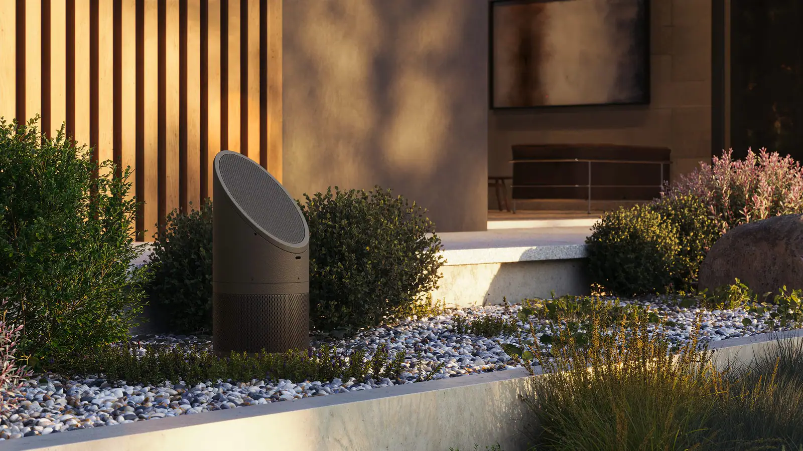 A sculptural landscape speaker among low planting in a modern garden at golden hour